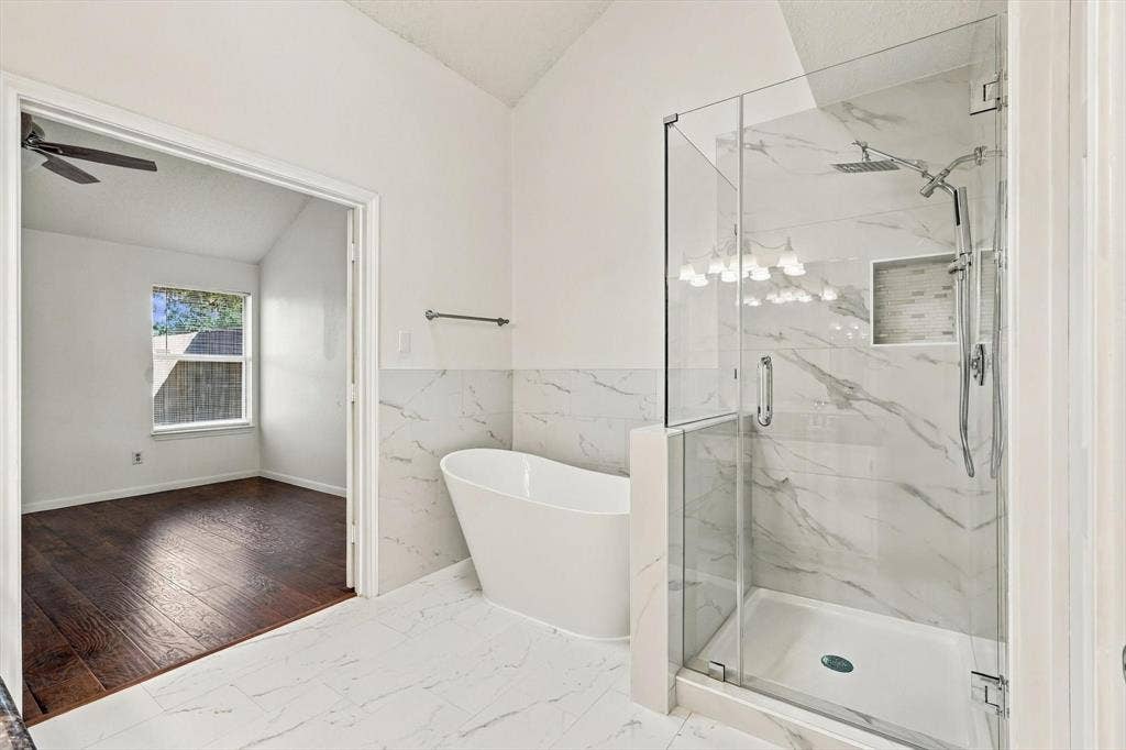 6821 Douglas Creek, Plano, TX 75023 Freestanding soaking tub, walk-in shower with frameless glass enclosure, and wall-to-wall stone-finish tile detailing