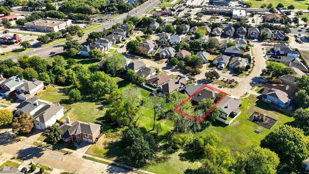6821 Douglas Creek, Plano, TX 75023 Aerial perspective of a residential property featuring a pitched composition shingle roof, expansive tree coverage, and an open grass lot
