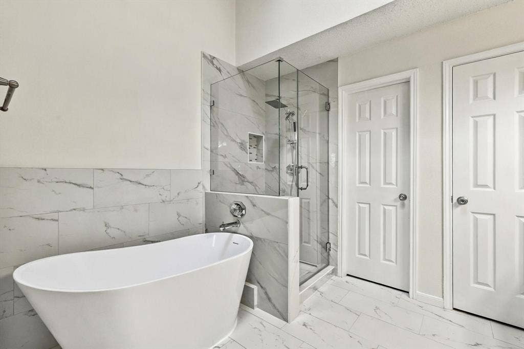 6821 Douglas Creek, Plano, TX 75023 Freestanding soaking tub paired with a glass-enclosed shower featuring large-format tile surround, recessed wall niche, and integrated rainfall showerhead