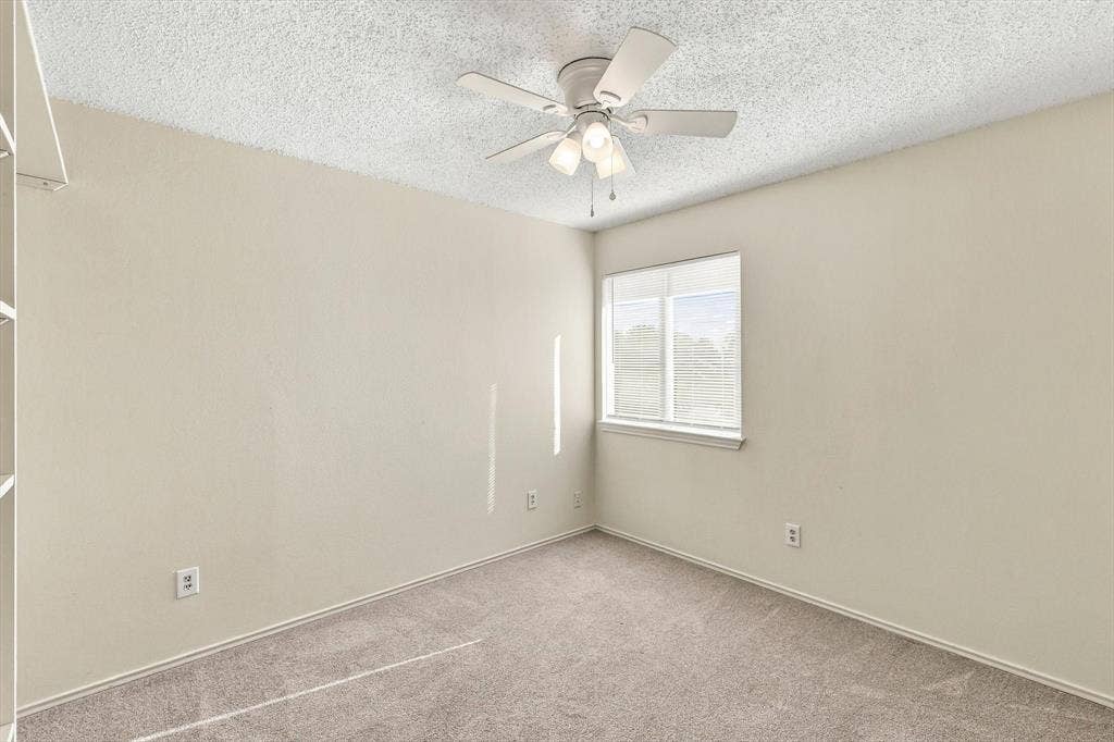6821 Douglas Creek, Plano, TX 75023 Neutral-toned interior space featuring carpeted flooring, textured ceiling, single window, and a multi-light ceiling fan