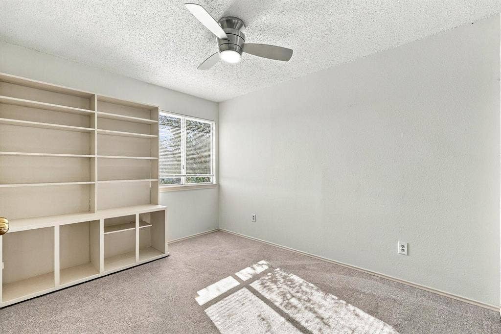 6821 Douglas Creek, Plano, TX 75023 Room featuring built-in floor-to-ceiling shelving, neutral carpeting, a dual-pane window, and a ceiling fan with integrated lighting