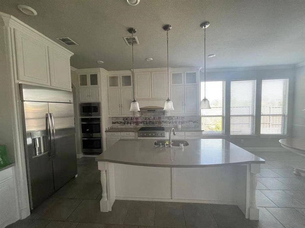 15112 Morning Star Lane, Frisco, TX 75035 Kitchen featuring an oversized central island with solid-surface countertop, white cabinetry, stainless steel professional-grade refrigerator, built-in double wall ovens, and recessed lighting