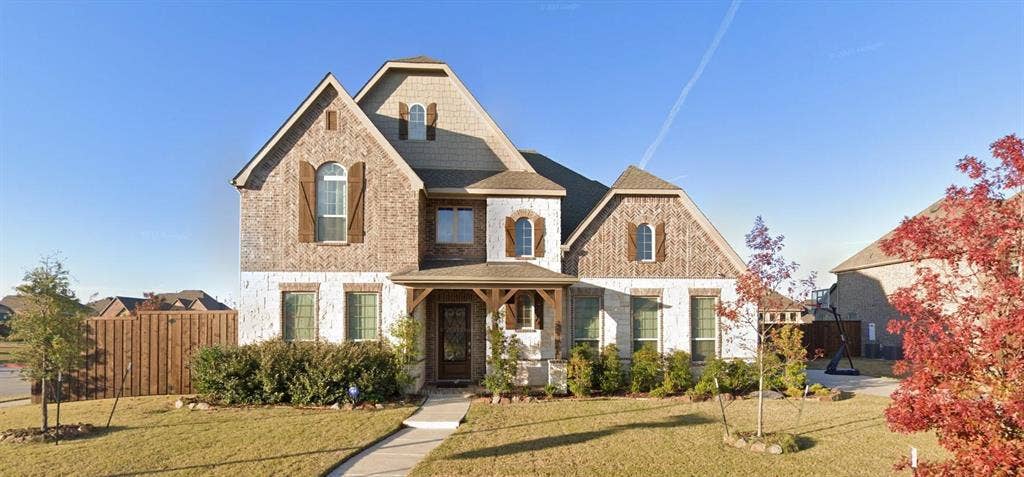 15112 Morning Star Lane, Frisco, TX 75035 Two-story residence featuring a multi-gabled roofline, mixed brick and stone facade, decorative wood shutters, and a covered front porch with timber-frame accents