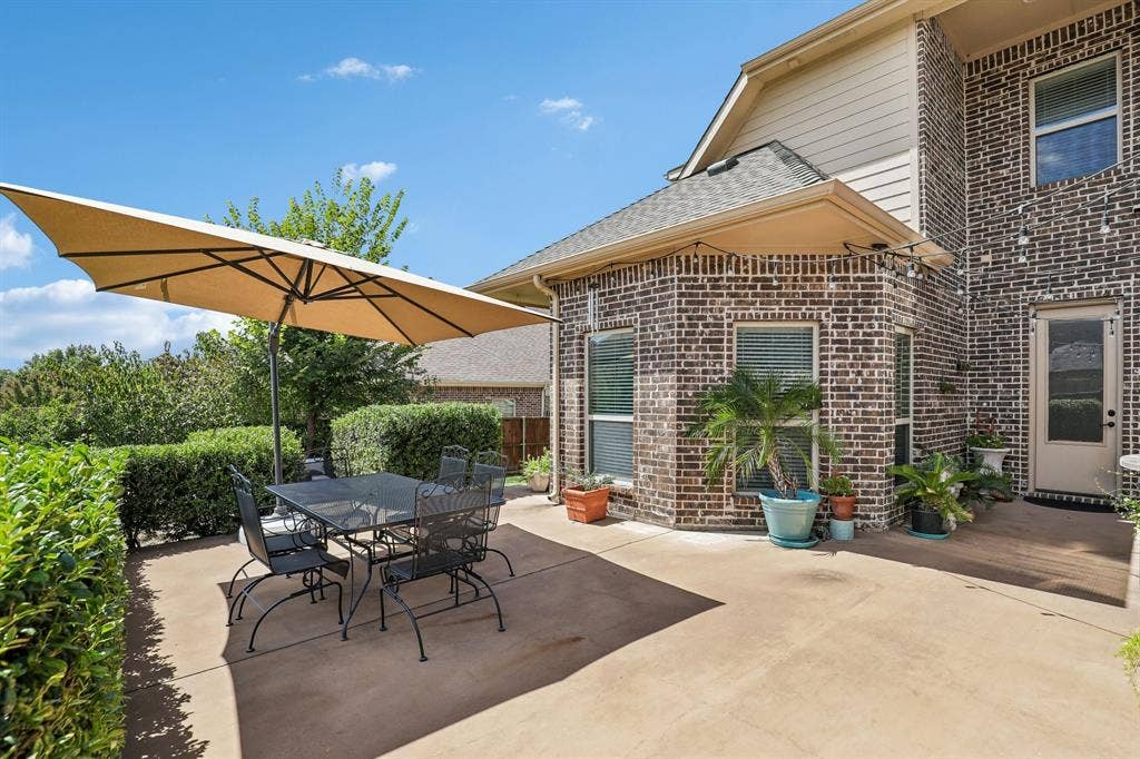 676 Princeton Way, Rockwall, TX 75087 Concrete patio featuring multi-toned brick masonry, fiber-cement siding, a prominent bay-style architectural element, and mature hedge landscaping