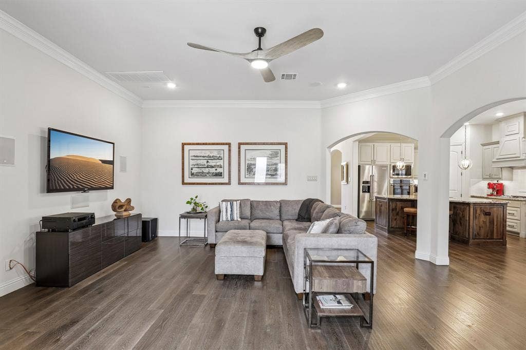 676 Princeton Way, Rockwall, TX 75087 Living area featuring wood-finish flooring, crown molding, a central ceiling fan with integrated lighting, and an arched entry