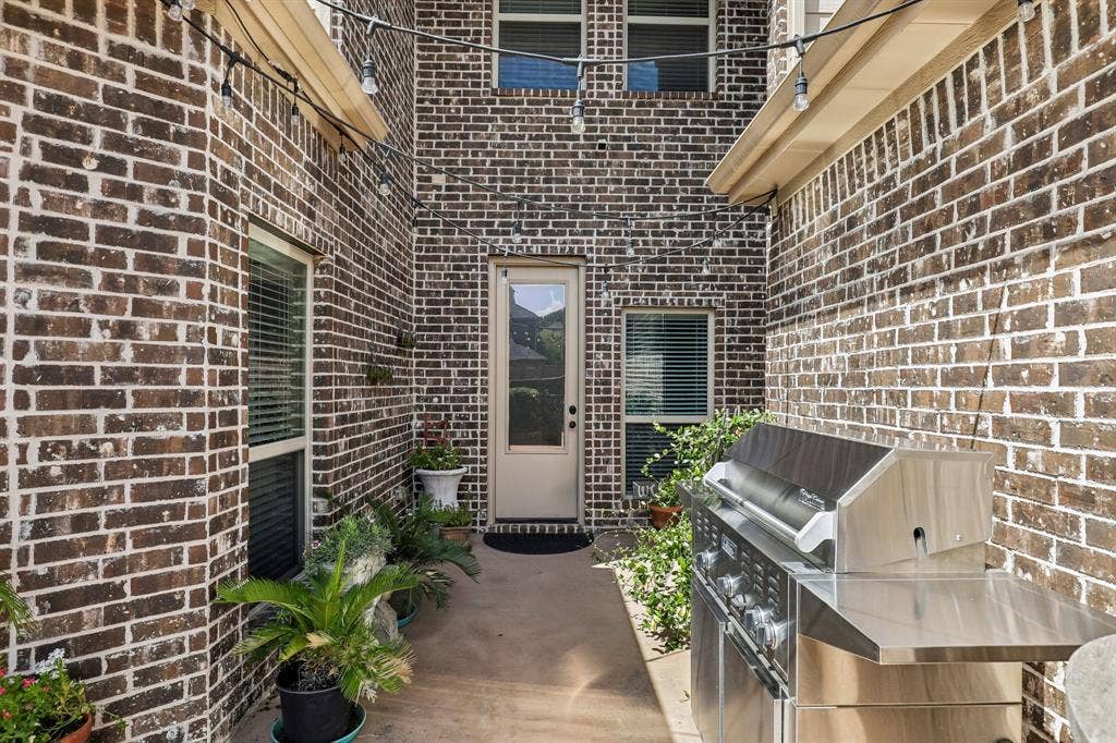 676 Princeton Way, Rockwall, TX 75087 Exterior brick courtyard featuring a concrete patio, built-in stainless steel grill, and string lighting