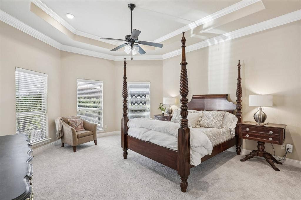 676 Princeton Way, Rockwall, TX 75087 Large primary bedroom with tray ceiling with crown molding, ceiling fan with integrated lighting, and multiple windows with horizontal blinds