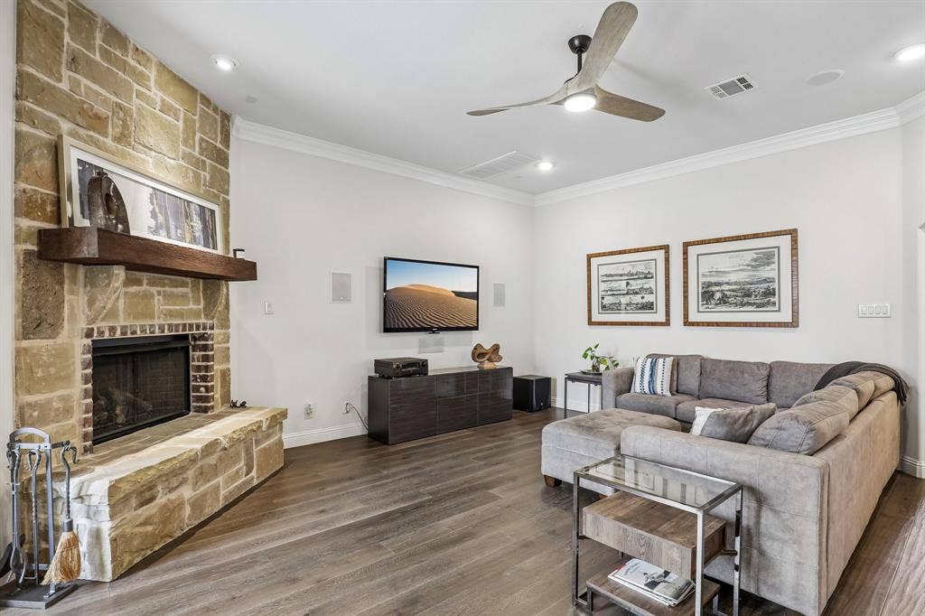 676 Princeton Way, Rockwall, TX 75087 Living area featuring a floor-to-ceiling stone fireplace, heavy timber mantel, wood-finish flooring, crown molding, and a modern ceiling fan