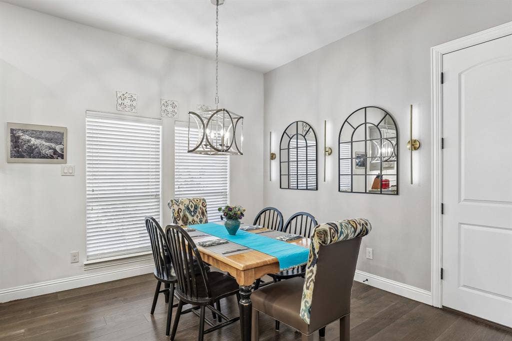 676 Princeton Way, Rockwall, TX 75087 Dining area featuring wood-finish flooring, a geometric metal chandelier, two arched wall-mounted mirrors, and sleek vertical accent lighting