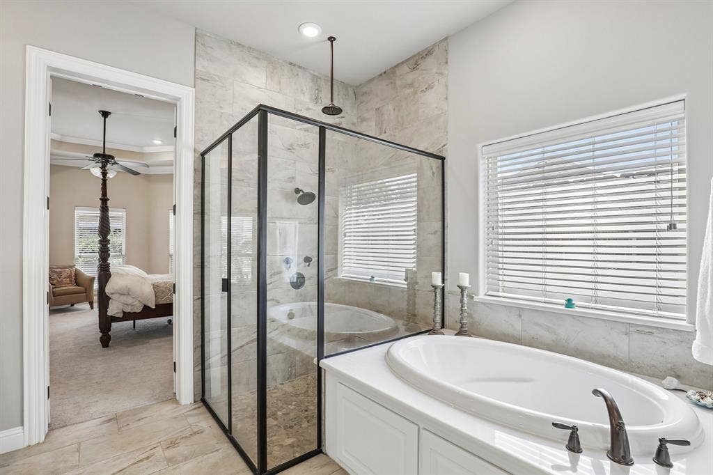 676 Princeton Way, Rockwall, TX 75087 Walk-in shower with matte black frame, large-format tile surround, rainfall showerhead, built-in soaking tub with deck-mount faucet, and wood-finish tile flooring in the primary bathroom