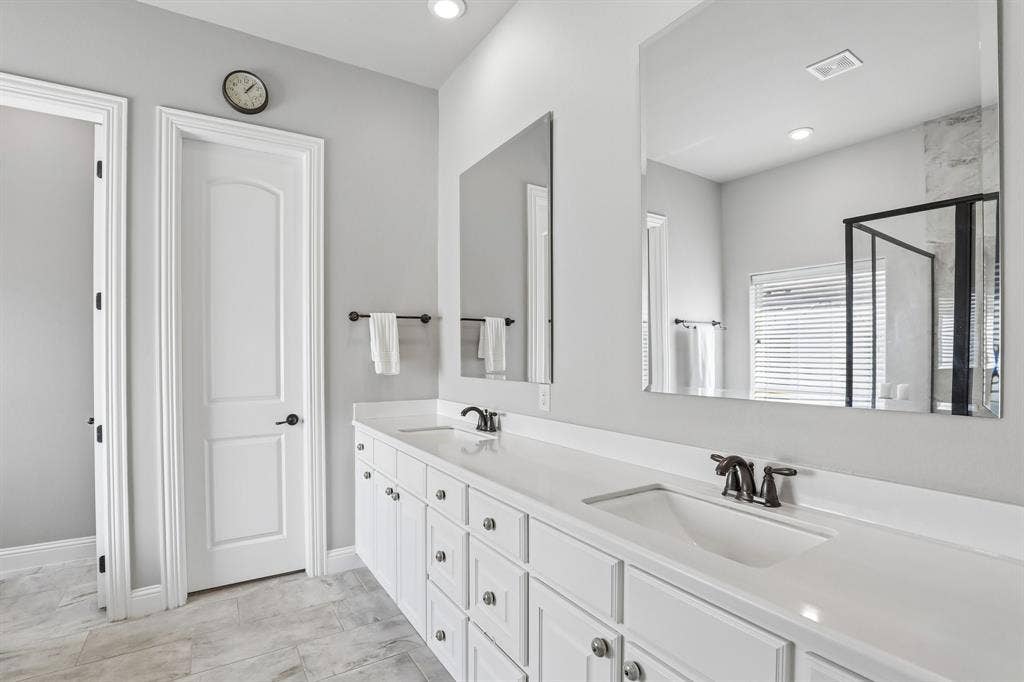 676 Princeton Way, Rockwall, TX 75087 Primary bath featuring dual-sink vanity with white cabinetry, light-toned countertop, rectangular undermount sinks, oil-rubbed bronze faucets, and oversized frameless wall-mounted mirrors