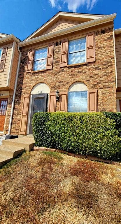 Multi-level brick exterior featuring arched window detailing, shutter accents, and a covered entry