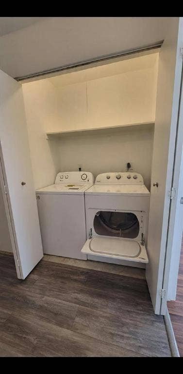 Laundry closet featuring wood-finish flooring, side-by-side washer and dryer, and an integrated overhead shelf
