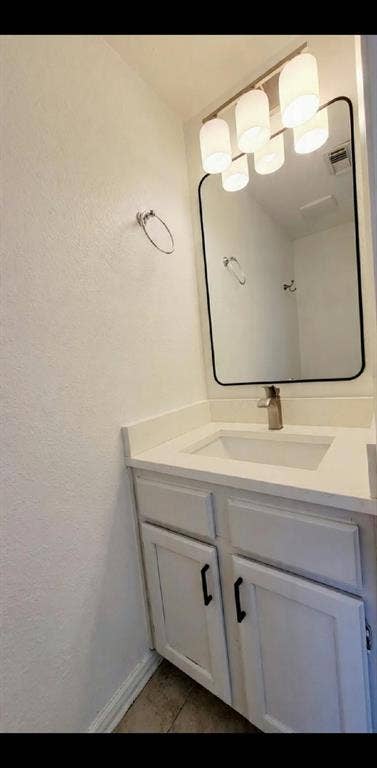 White vanity cabinet with matte black hardware, integrated rectangular sink, solid surface countertop, wall-mounted rectangular mirror with rounded corners, and multi-bulb glass light fixture