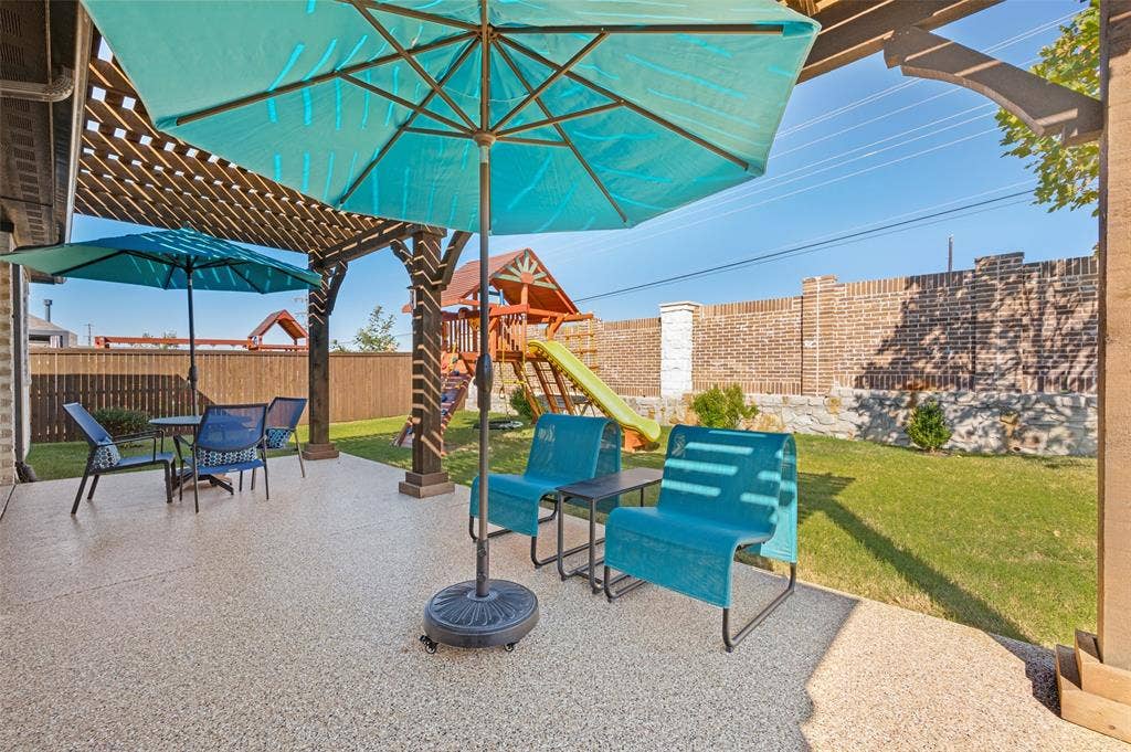 3417 Paintbrush Path, Melissa, TX 75454 Covered patio featuring a textured concrete finish, overhead timber pergola, brick perimeter wall, and a grass lawn