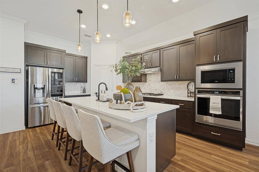 3417 Paintbrush Path, Melissa, TX 75454 Kitchen featuring dark-finish cabinetry, quartz countertops, a central island, wood-finish flooring, and stainless steel built-in appliances
