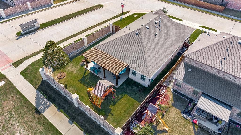 3417 Paintbrush Path, Melissa, TX 75454 Aerial perspective of a corner lot property featuring a stone and brick perimeter wall, a covered patio with a wooden pergola, and a private lawn area