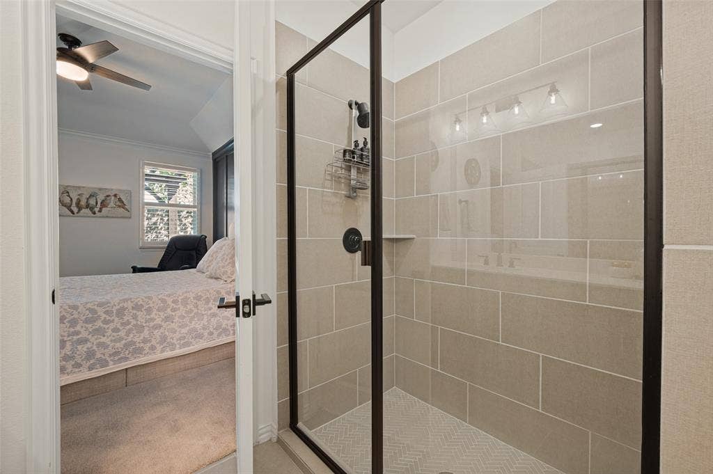 3417 Paintbrush Path, Melissa, TX 75454 Walk-in shower featuring large-format beige wall tile, herringbone-patterned floor tile, matte black hardware, and a glass enclosure with a black frame