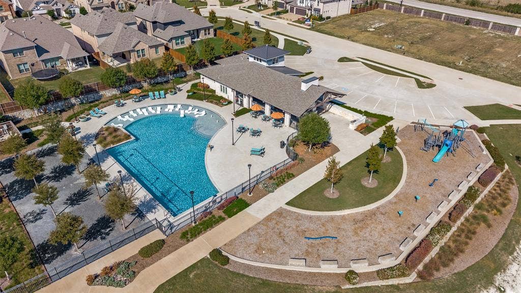 3417 Paintbrush Path, Melissa, TX 75454 Community amenity center featuring a swimming pool with a shallow sun shelf, expansive concrete decking, a covered pavilion, and a playground with mulch surfacing