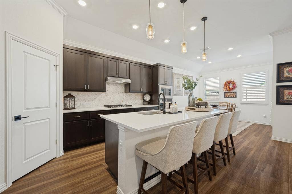 3417 Paintbrush Path, Melissa, TX 75454 Kitchen featuring dark wood cabinetry, quartz countertops, a stone-patterned backsplash, wood-finish flooring, and pendant lighting