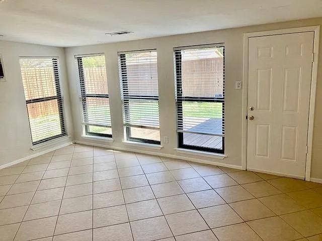 407 Cambridge Drive, Richardson, TX 75080 Neutral tile flooring, multiple windows with horizontal blinds, and a paneled exterior access door