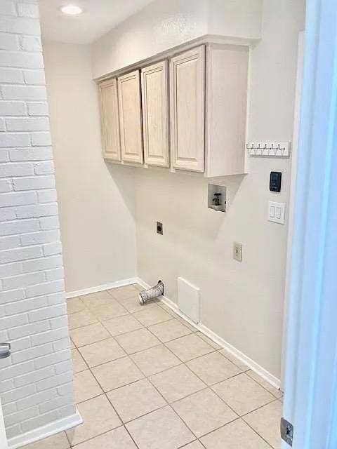 407 Cambridge Drive, Richardson, TX 75080 Utility room featuring ceramic tile flooring, painted brick wall detail, and upper cabinetry for storage