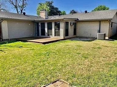 407 Cambridge Drive, Richardson, TX 75080 Exterior featuring light-colored brick siding, a wood deck, and a shingled roof