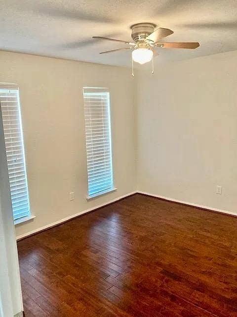 407 Cambridge Drive, Richardson, TX 75080 Room featuring wood-finish flooring, two windows with horizontal blinds, and a ceiling fan with integrated lighting