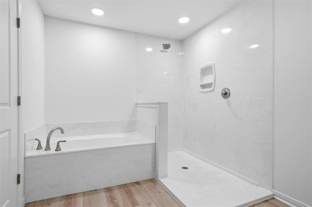 2303 Pilgrim Lane, Lorena, TX 76655 Soaking tub with a curved faucet, separate walk-in shower featuring a built-in recessed soap niche, light-toned wood-finish flooring, and recessed ceiling lighting