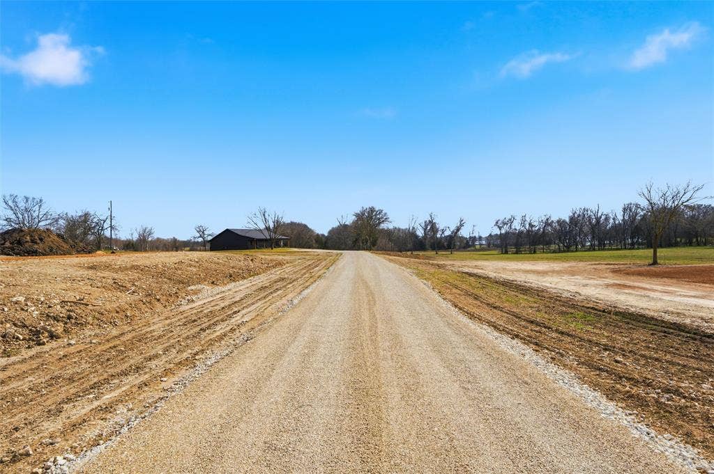 2303 Pilgrim Lane, Lorena, TX 76655 Expansive cleared acreage featuring a gravel road, level topography, and mature trees