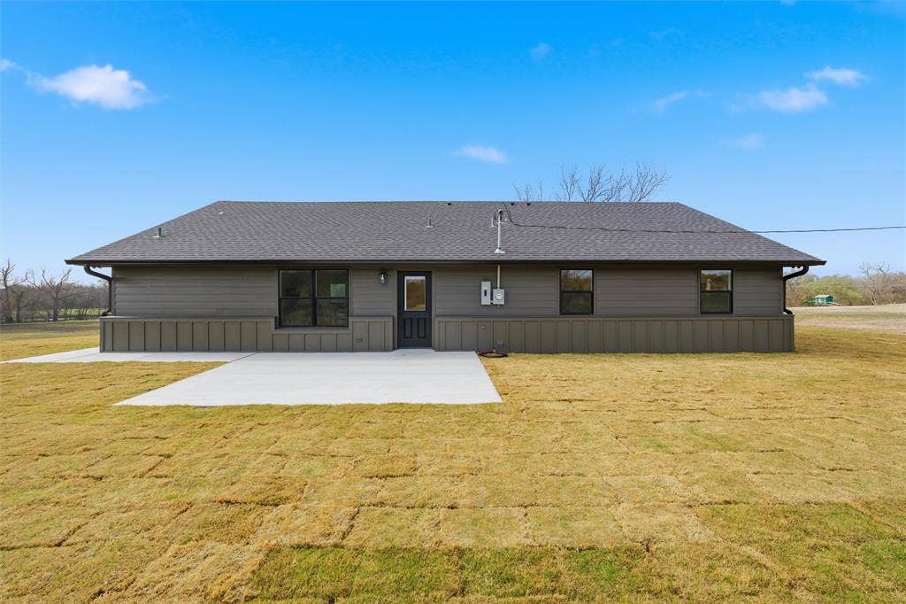 2303 Pilgrim Lane, Lorena, TX 76655 Exterior rear facade featuring dark-toned siding, a combination of board-and-batten and horizontal paneling, a gabled roofline, and a poured concrete patio