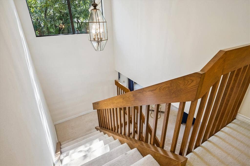 2926 N Saint Andrews Drive, Richardson, TX 75082 View from the top of the wooden staircase with a large window bringing in natural light into the home and a nice light fixture.