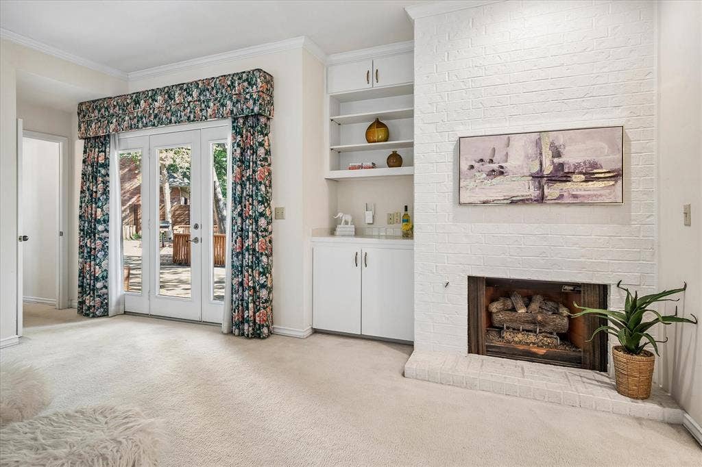 2926 N Saint Andrews Drive, Richardson, TX 75082 Another view of the primary bedroom with built-ins and a gas log fireplace providing ambiance to the room. The door leads to the spacious outdoor deck providing spectacular views of the large backyard creek lot.