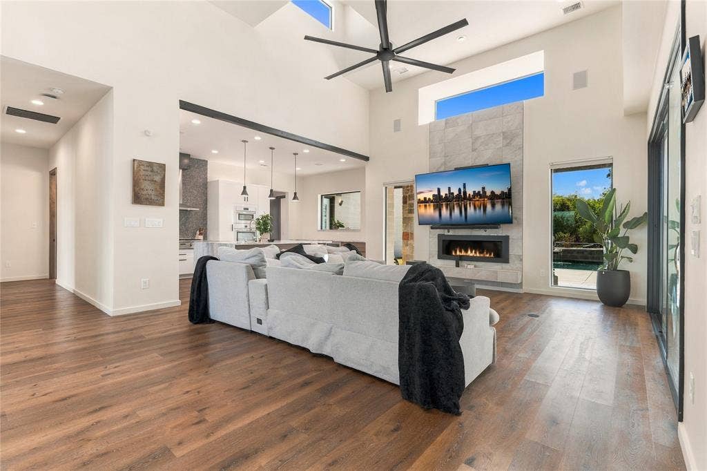 211 Hunter Pass, Waxahachie, TX 75165 Vaulted ceilings with transom windows, stone-clad gas fireplace, wood-finish flooring, recessed lighting, and multi-panel sliding glass doors