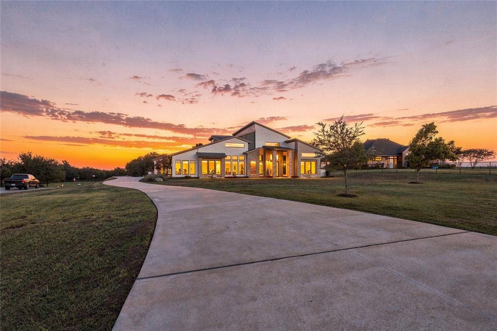 211 Hunter Pass, Waxahachie, TX 75165 Contemporary residence featuring a multi-gabled roofline, stone and stucco exterior, expansive windows, and a paved private driveway set on a landscaped lot