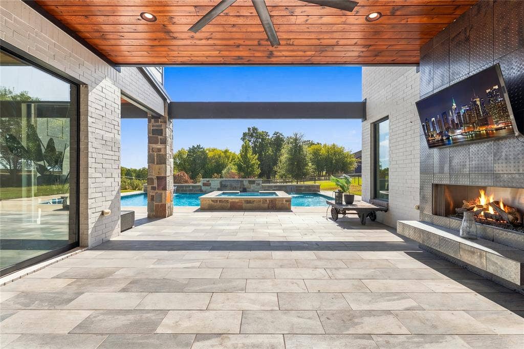 211 Hunter Pass, Waxahachie, TX 75165 Covered outdoor patio featuring a wood-plank ceiling, floor-to-ceiling stone-surround fireplace, tile flooring, and integrated recessed lighting, opening to a swimming pool and spa