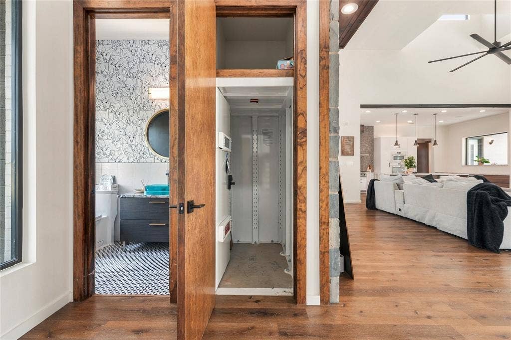 211 Hunter Pass, Waxahachie, TX 75165 Interior residential elevator featuring an industrial-style metal cab, wood-finish flooring, and natural wood door casing