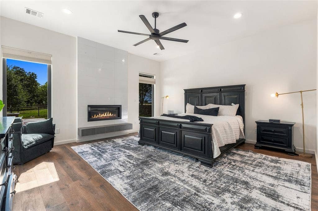 211 Hunter Pass, Waxahachie, TX 75165 Spacious room featuring wood-finish flooring, a linear fireplace with a floor-to-ceiling tile surround, a cantilevered hearth, and a modern six-blade ceiling fan