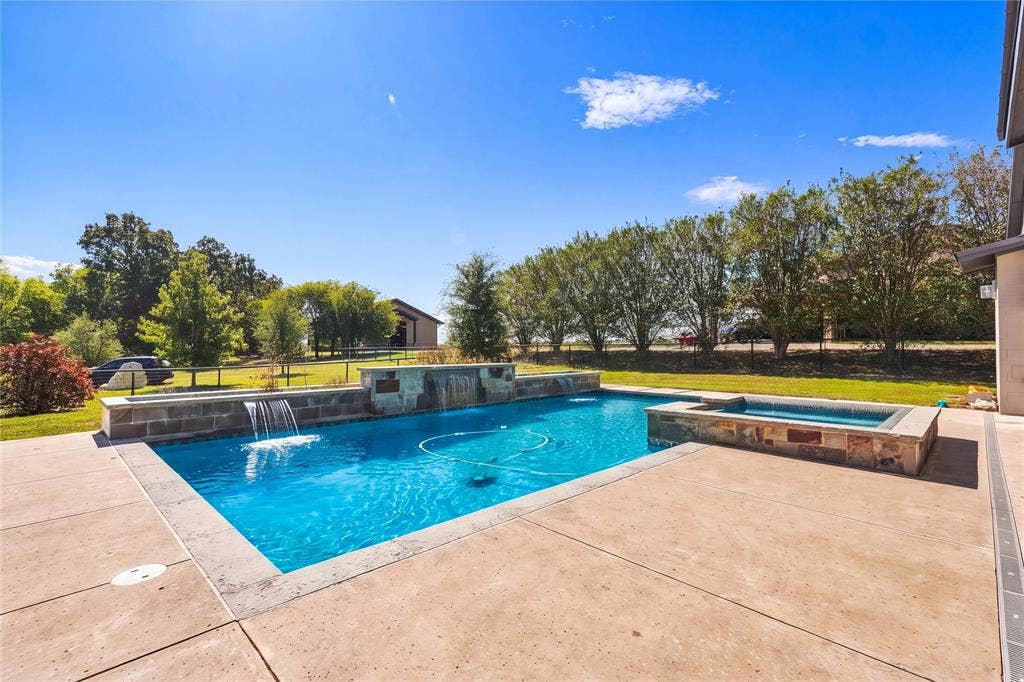 211 Hunter Pass, Waxahachie, TX 75165 Backyard swimming pool featuring stone accents, a raised spa, water features, and a concrete patio