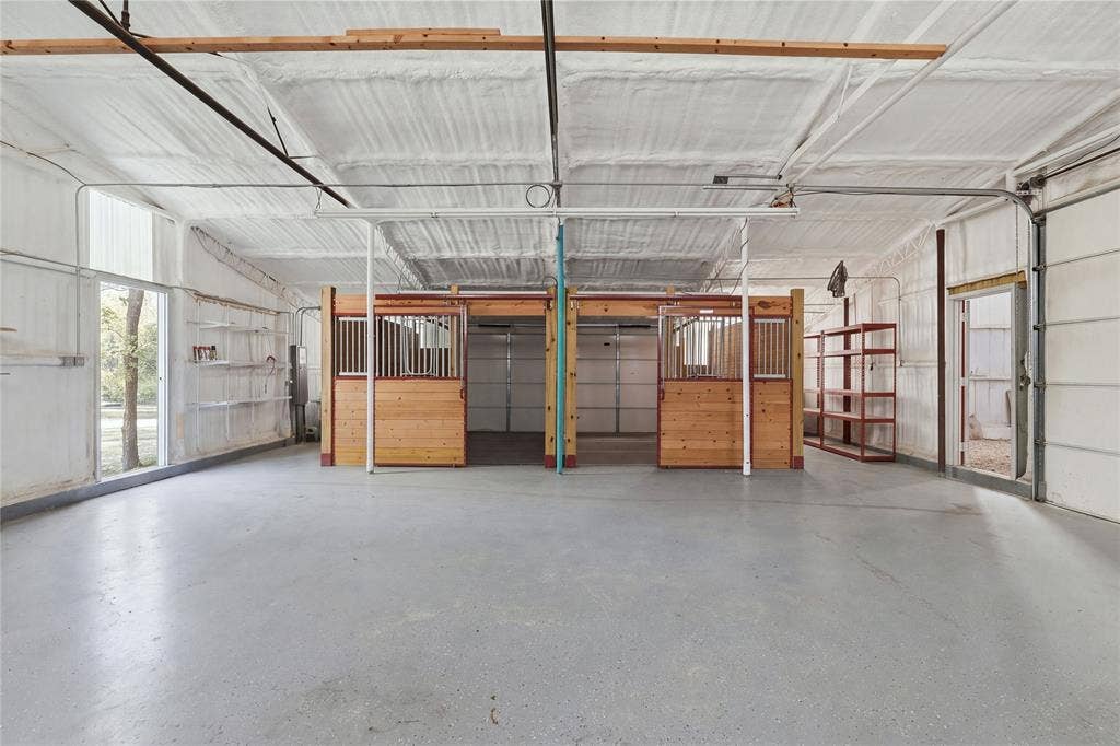 211 Hunter Pass, Waxahachie, TX 75165 Spacious multipurpose outbuilding featuring concrete flooring, spray-foam insulation, and three wooden horse stalls with metal grating