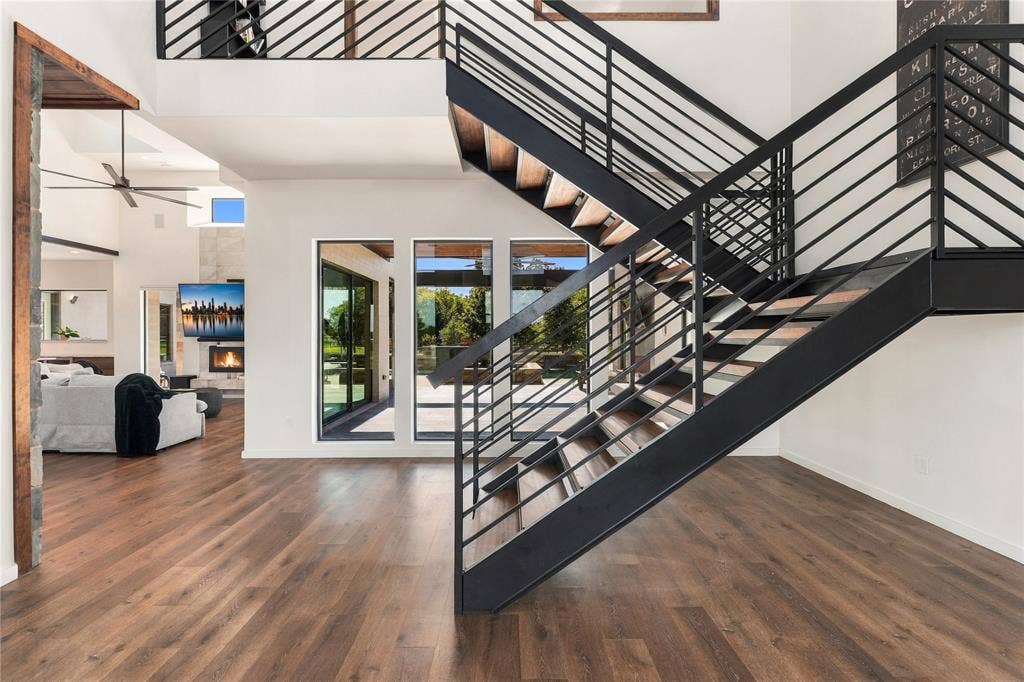 211 Hunter Pass, Waxahachie, TX 75165 Open-concept interior featuring wood-finish flooring, a floating staircase with black metal railings, triple-pane windows, and high ceilings