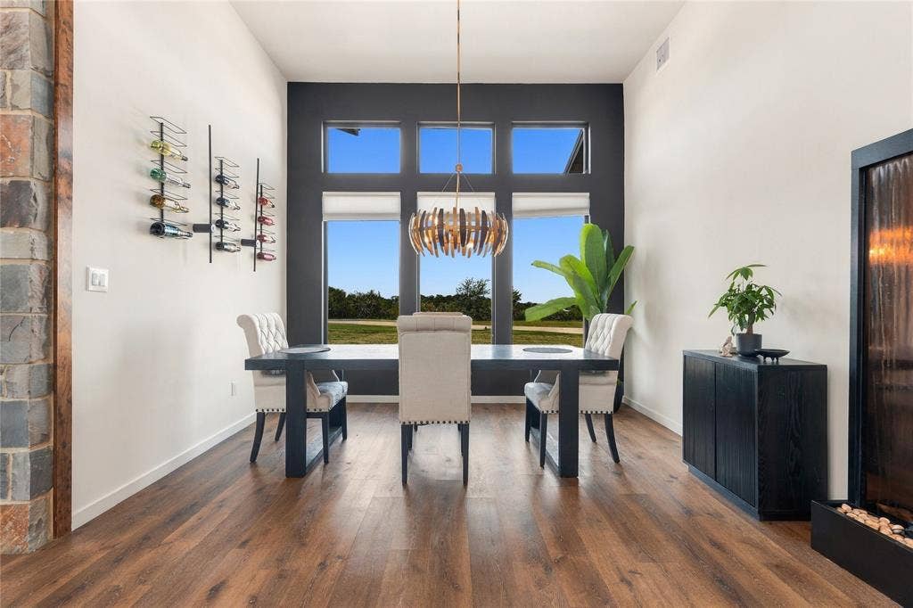 211 Hunter Pass, Waxahachie, TX 75165 High ceilings featuring oversized windows, wood-finish flooring, wall-mounted wine storage, and a tiered metallic pendant light fixture