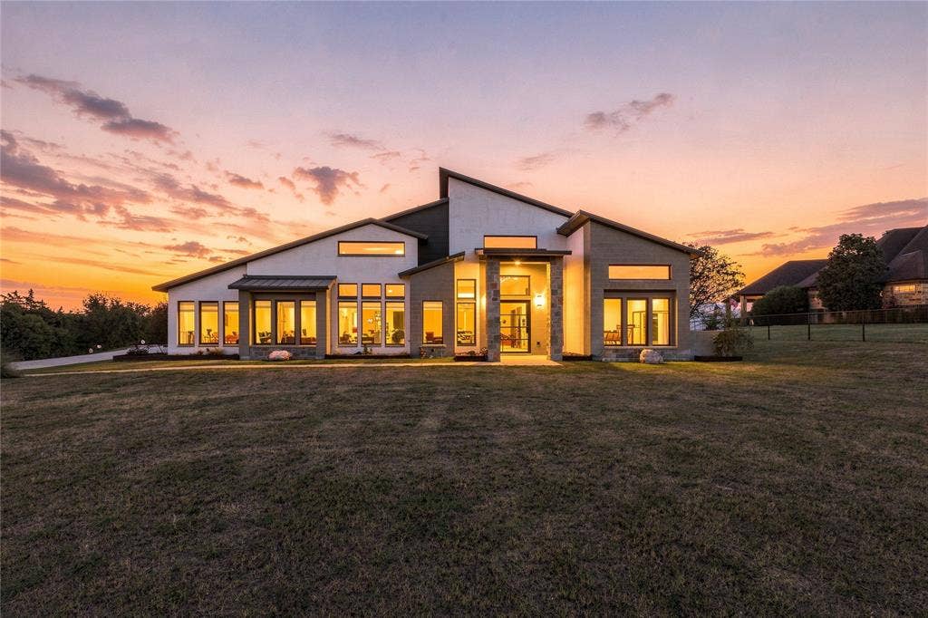 211 Hunter Pass, Waxahachie, TX 75165 Modern architectural exterior featuring a multi-pitched roofline, stone veneer accents, stucco siding, and extensive floor-to-ceiling windows