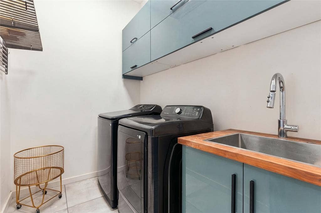 211 Hunter Pass, Waxahachie, TX 75165 Laundry room featuring slate blue cabinetry with matte black hardware, a wood-finish countertop, a stainless steel undermount sink, and a high-arch pull-down faucet