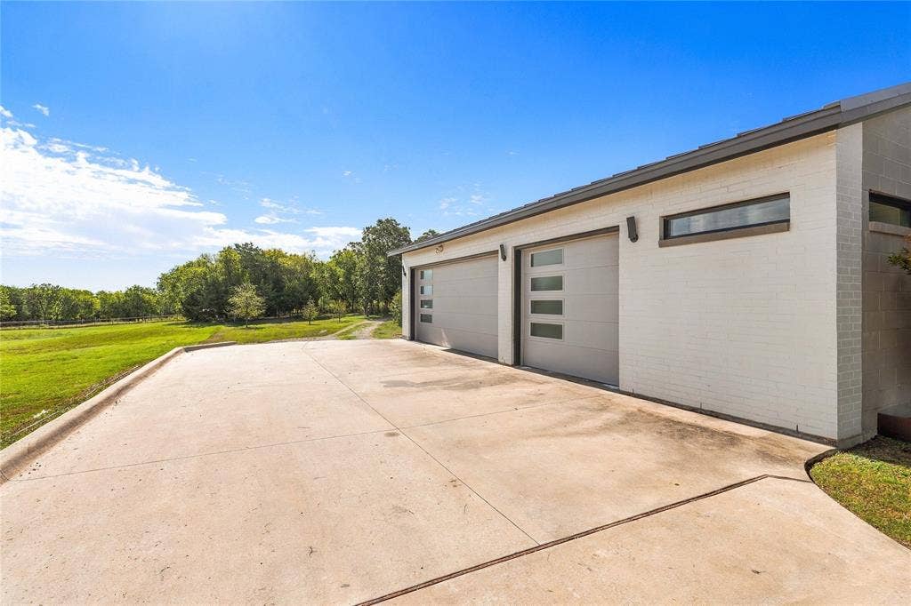 211 Hunter Pass, Waxahachie, TX 75165 Detached structure featuring a white painted brick exterior, two garage bays with horizontal glass-panel accents, and a concrete apron