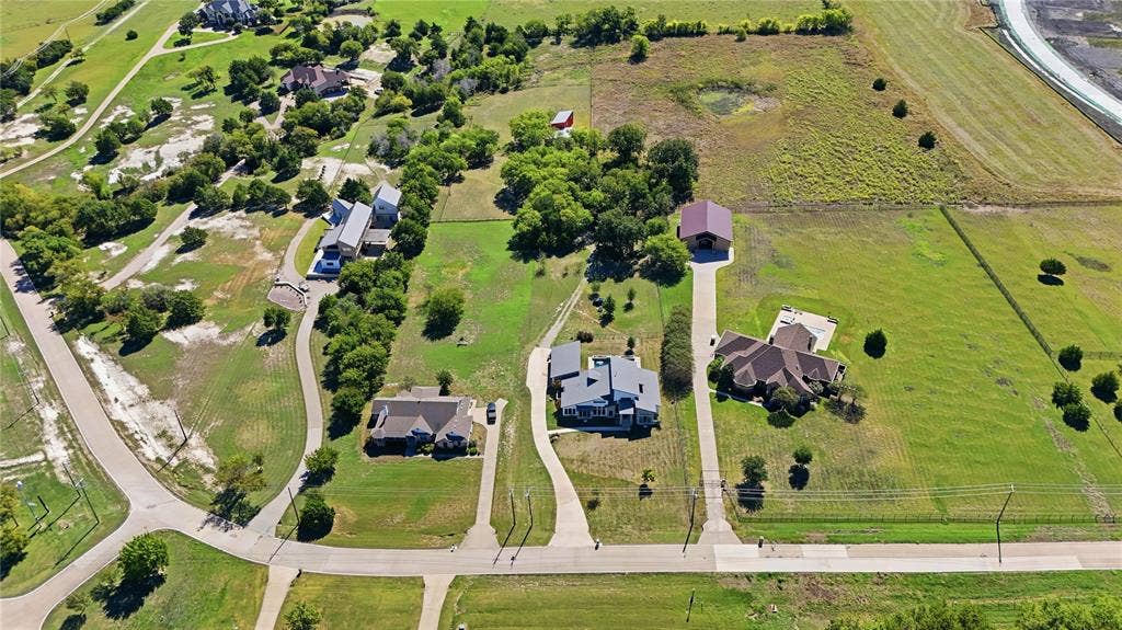 211 Hunter Pass, Waxahachie, TX 75165 Aerial perspective of expansive acreage featuring multiple residential structures, concrete driveways, and detached outbuildings situated among mature trees and open green space