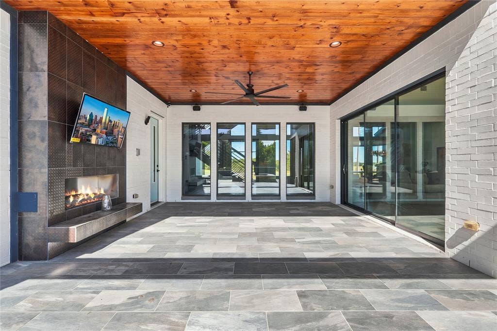 211 Hunter Pass, Waxahachie, TX 75165 Covered patio featuring a natural wood-finish plank ceiling, large-format tile flooring, a floor-to-ceiling tiled fireplace surround, and expansive sliding glass doors