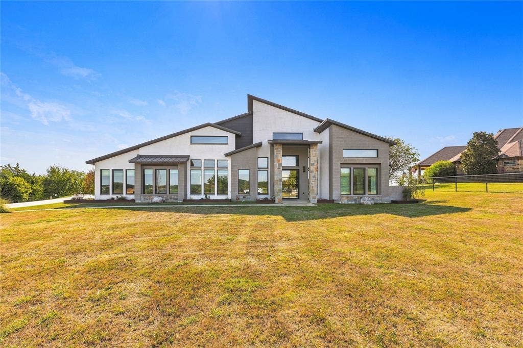 211 Hunter Pass, Waxahachie, TX 75165 Modern exterior featuring a multi-gabled roofline, stone masonry accents, a stucco facade, and oversized picture windows