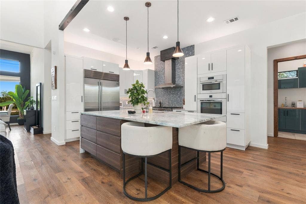 211 Hunter Pass, Waxahachie, TX 75165 Kitchen featuring high-gloss white cabinetry, wood-finish center island with stone countertop, stainless steel appliances, textured tile backsplash, and recessed lighting