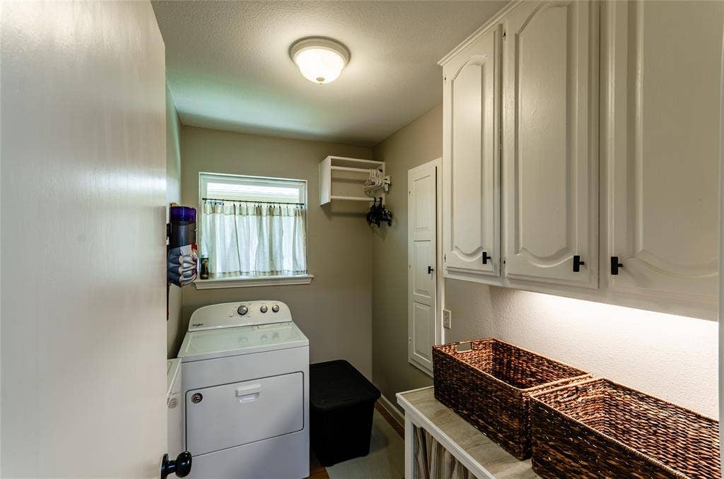 White cabinetry with dark hardware, built-in shelving, and a window for natural light